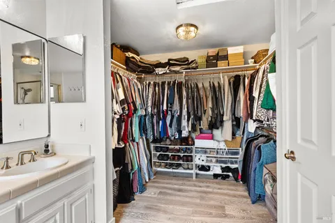 a view of walk in closet with clothes and shoes