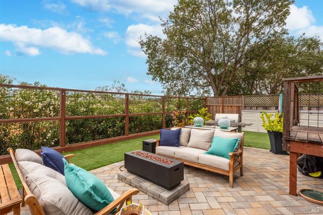 a view of a patio with couches chairs and a fire pit with large trees