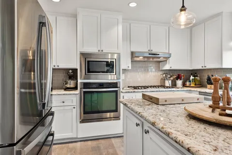 a kitchen with stainless steel appliances granite countertop a stove a refrigerator and a sink