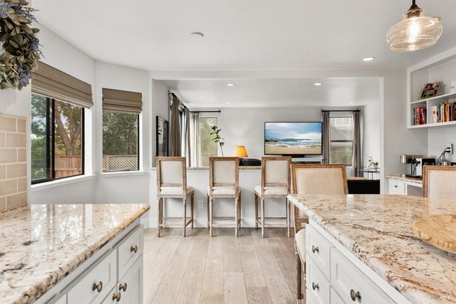 a kitchen with stainless steel appliances granite countertop a table chairs and a large window