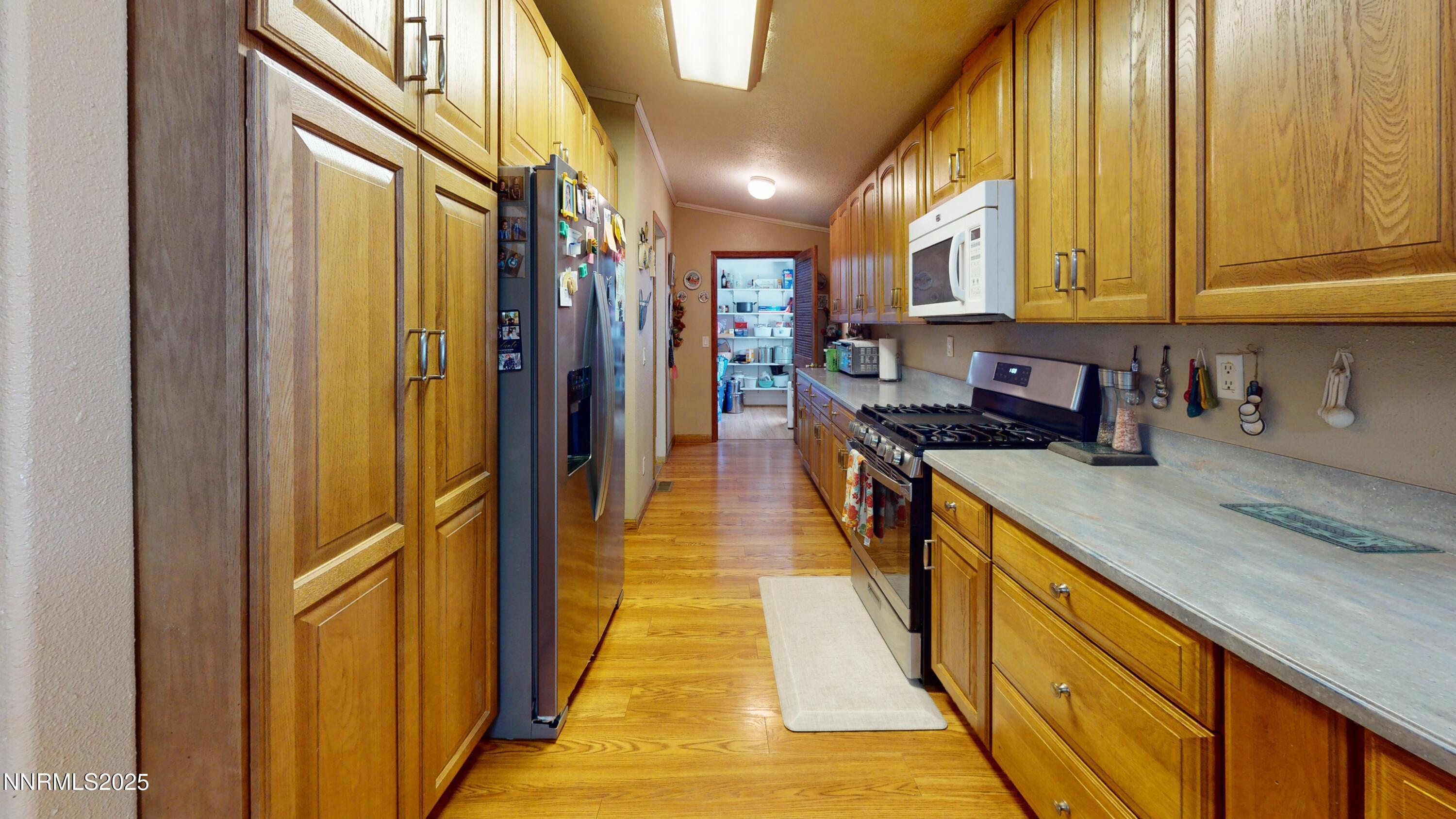3400 Potbelly Road Winnemucca, NV 89445 - Photo 9 of 50 a hallway with stainless steel appliances granite countertop a sink and a refrigerator