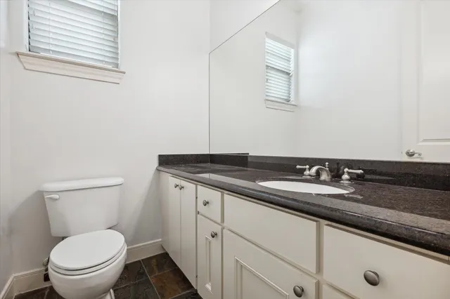 a bathroom with a granite countertop toilet a sink and a mirror