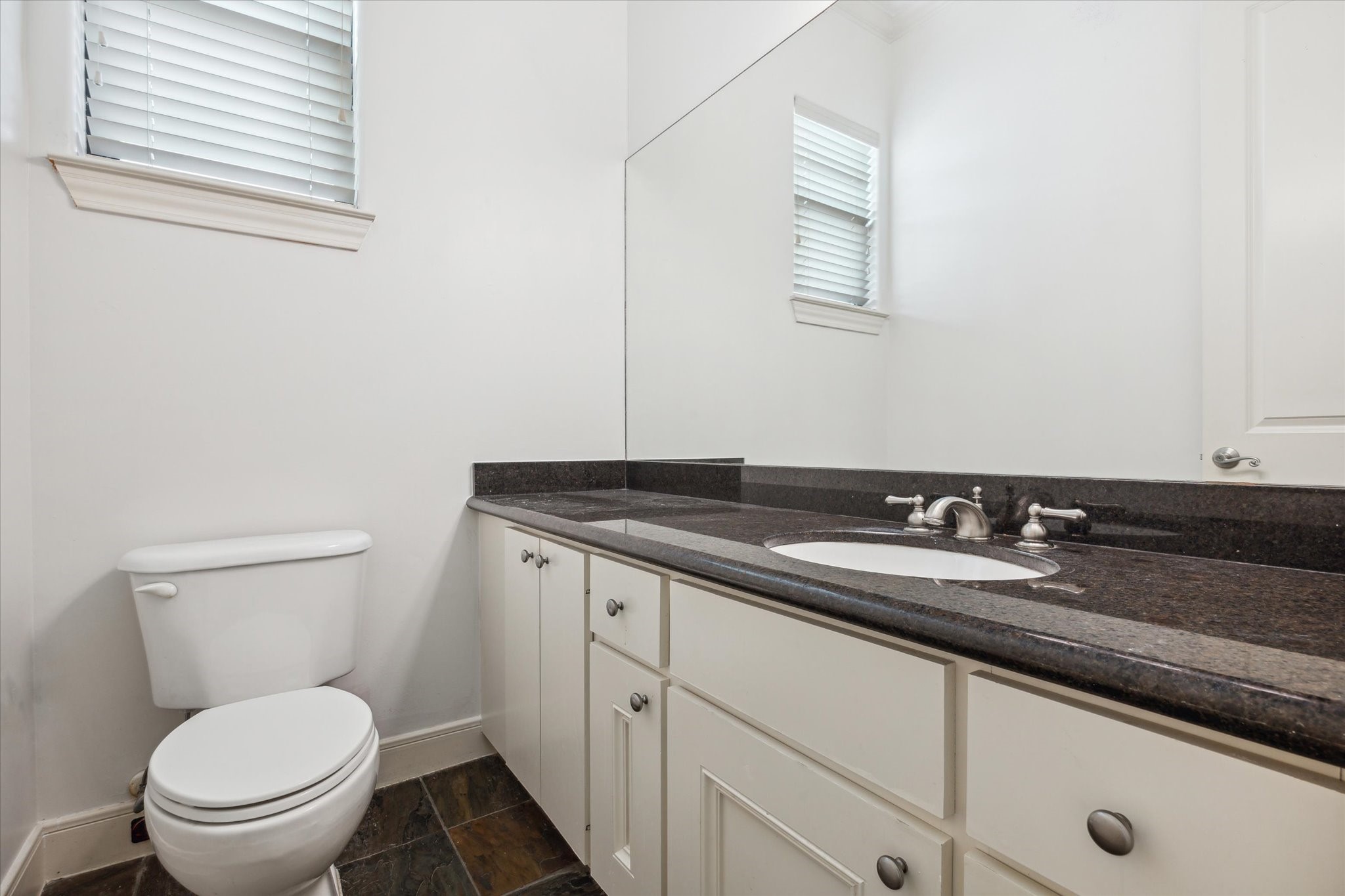 1826 Colquitt Street Houston, TX 77098 - Photo 11 of 23 a bathroom with a granite countertop toilet a sink and a mirror