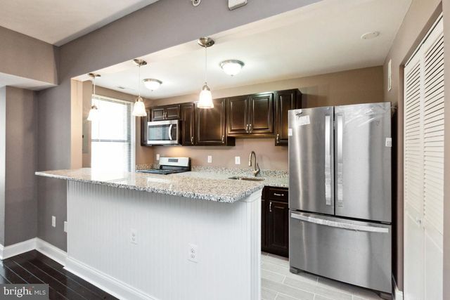 a kitchen with stainless steel appliances granite countertop a refrigerator a sink a stove a microwave and island