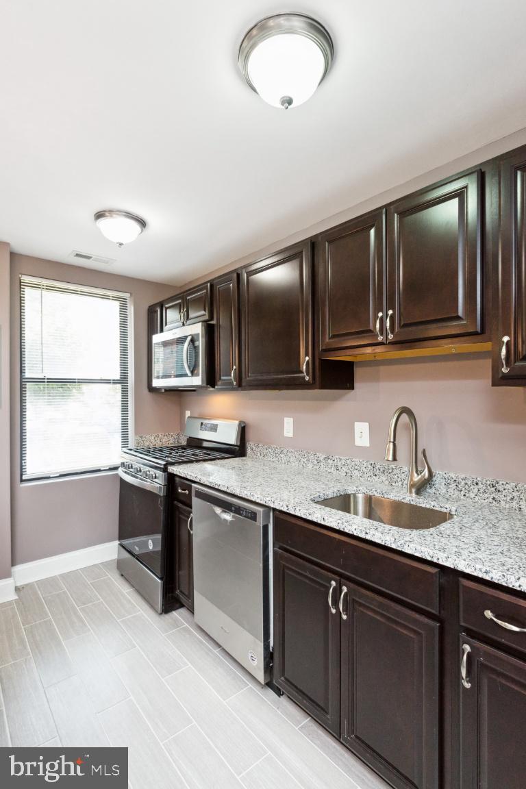 3900 14th Street Northwest, Unit 103 Washington, DC 20011 - Photo 13 of 29 a kitchen with stainless steel appliances granite countertop a sink and stove top oven