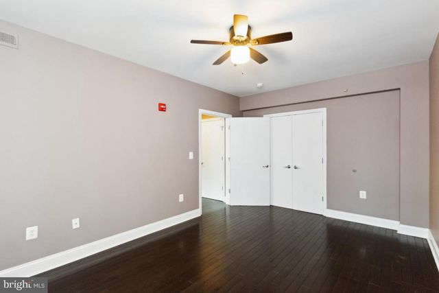 an empty room with wooden floor and ceiling fan
