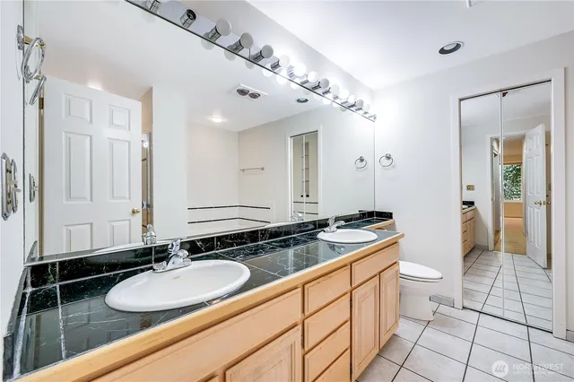 a bathroom with a granite countertop sink a toilet a mirror and vanity