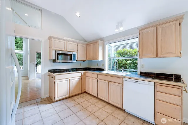 a kitchen with granite countertop white cabinets white appliances a sink and a window