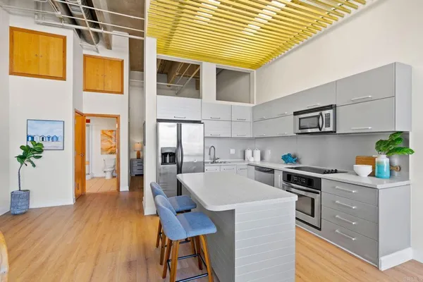 a kitchen with stainless steel appliances furniture wooden floor and a refrigerator