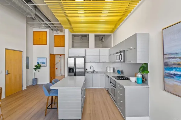 a kitchen with counter top space a sink a refrigerator and chairs