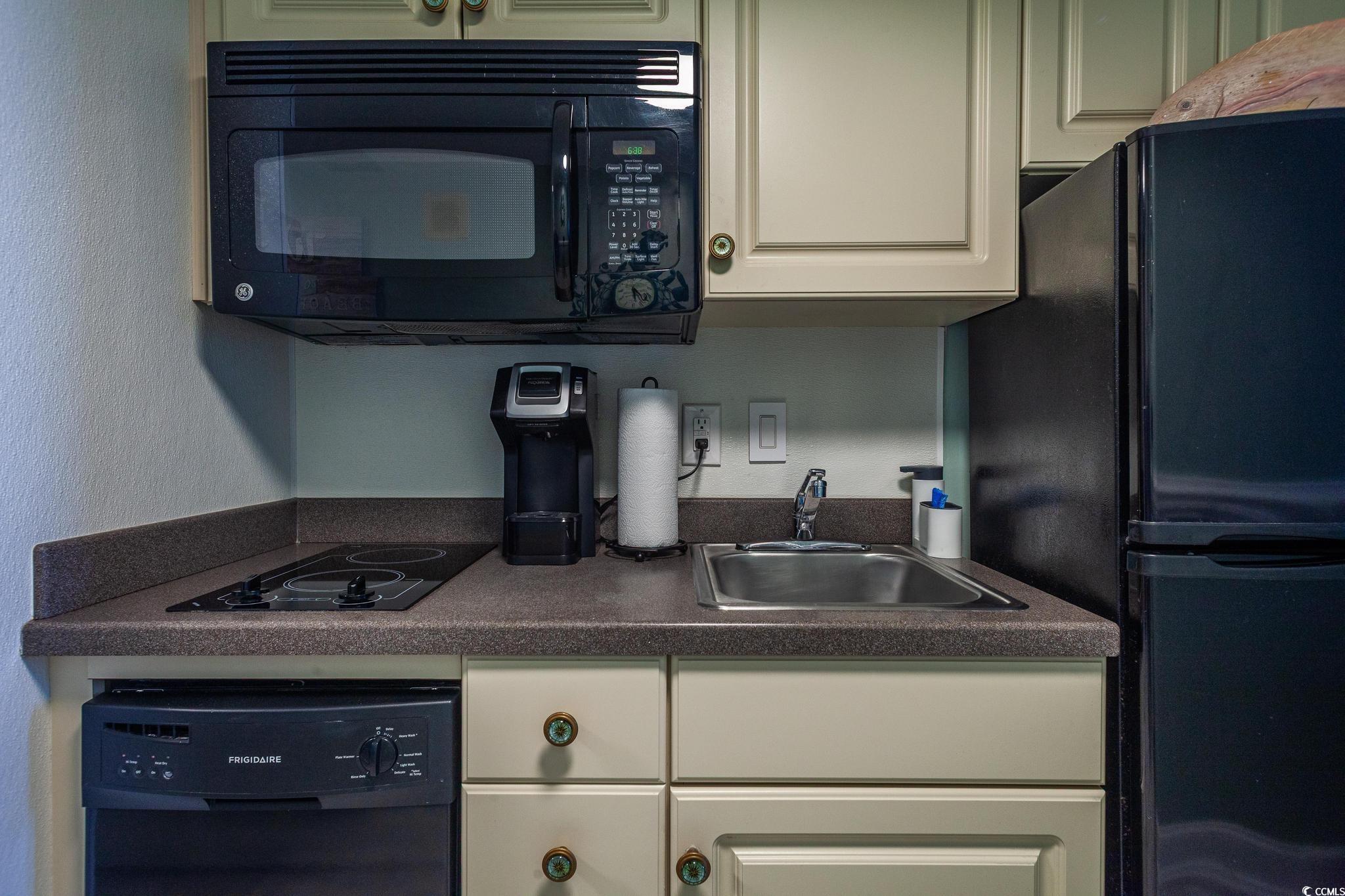 9550 Shore Drive, Unit 1728 Myrtle Beach, SC 29572 - Photo 11 of 36 Kitchen featuring black appliances, dark countertops, white cabinets, and a textured wall
