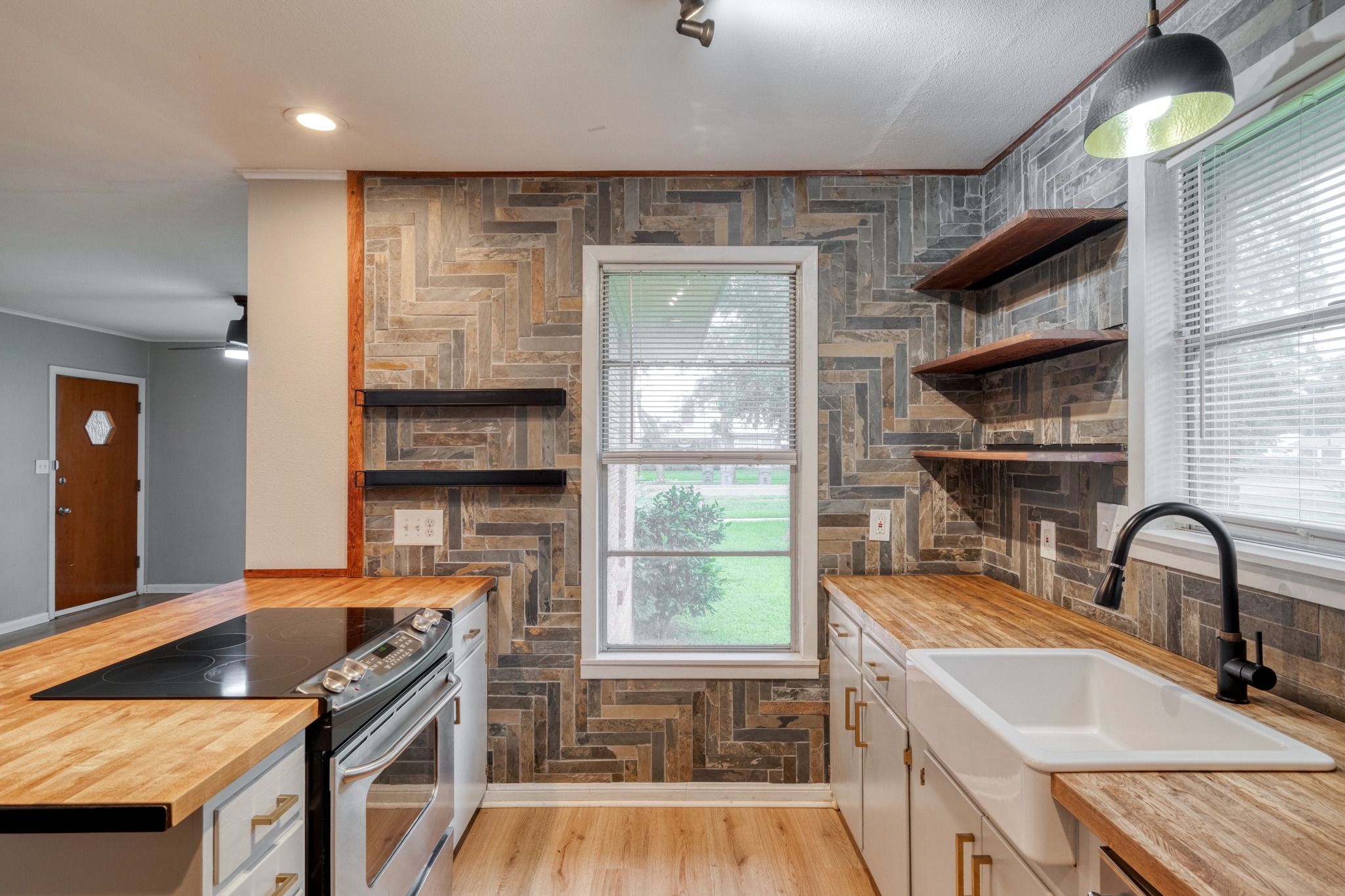 707 North Main Street Elgin, TX 78621 - Photo 12 of 21 Kitchen with stair-step tile accent wall, window, open shelving, farmhouse sink and butcher block counters