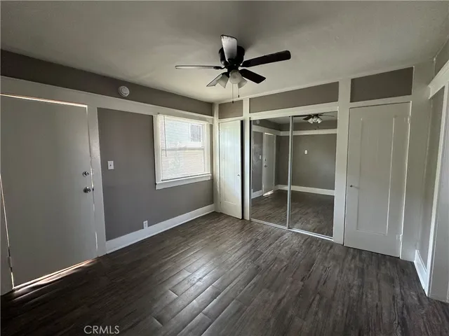 an empty room with wooden floor a ceiling fan and windows