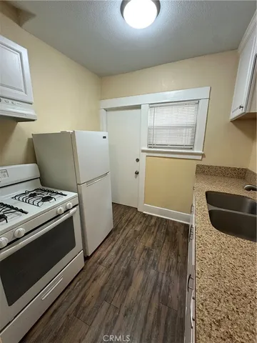a kitchen with a stove wooden floor and a sink
