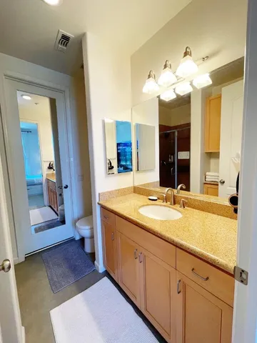 a spacious bathroom with a granite countertop sink a mirror and a bathtub