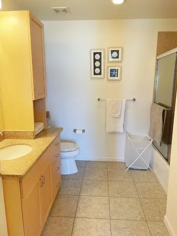 a bathroom with a granite countertop sink a toilet and a mirror