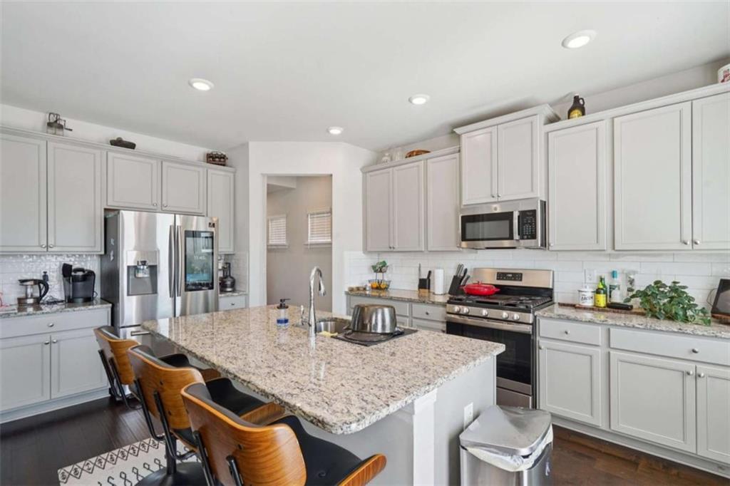 3605 Broadwick Lane Lithonia, GA 30038 - Photo 9 of 41 a kitchen with stainless steel appliances granite countertop a kitchen island hardwood floor sink stove and white cabinets