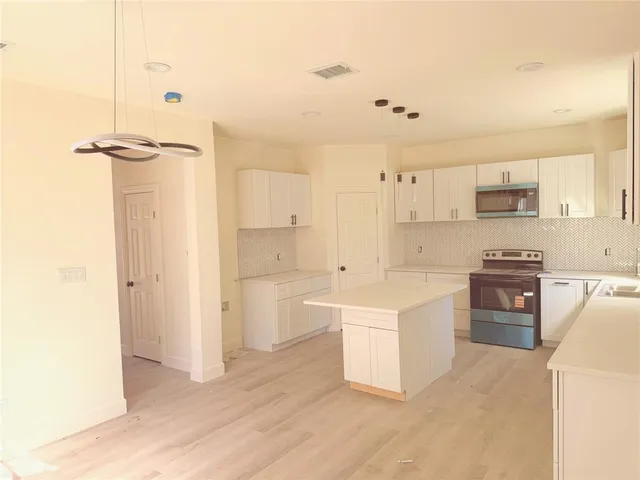 a kitchen with a refrigerator a stove top oven and white cabinets