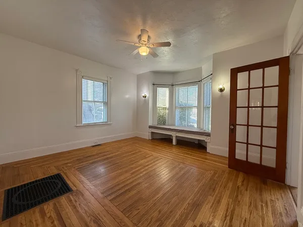 an empty room with windows and ceiling fan