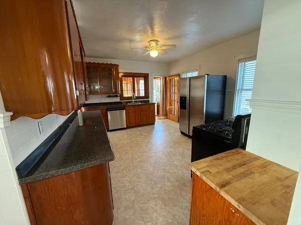 a kitchen with stainless steel appliances granite countertop a refrigerator a stove and a sink with wooden floor