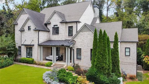 a view of a white house next to a yard with plants and trees