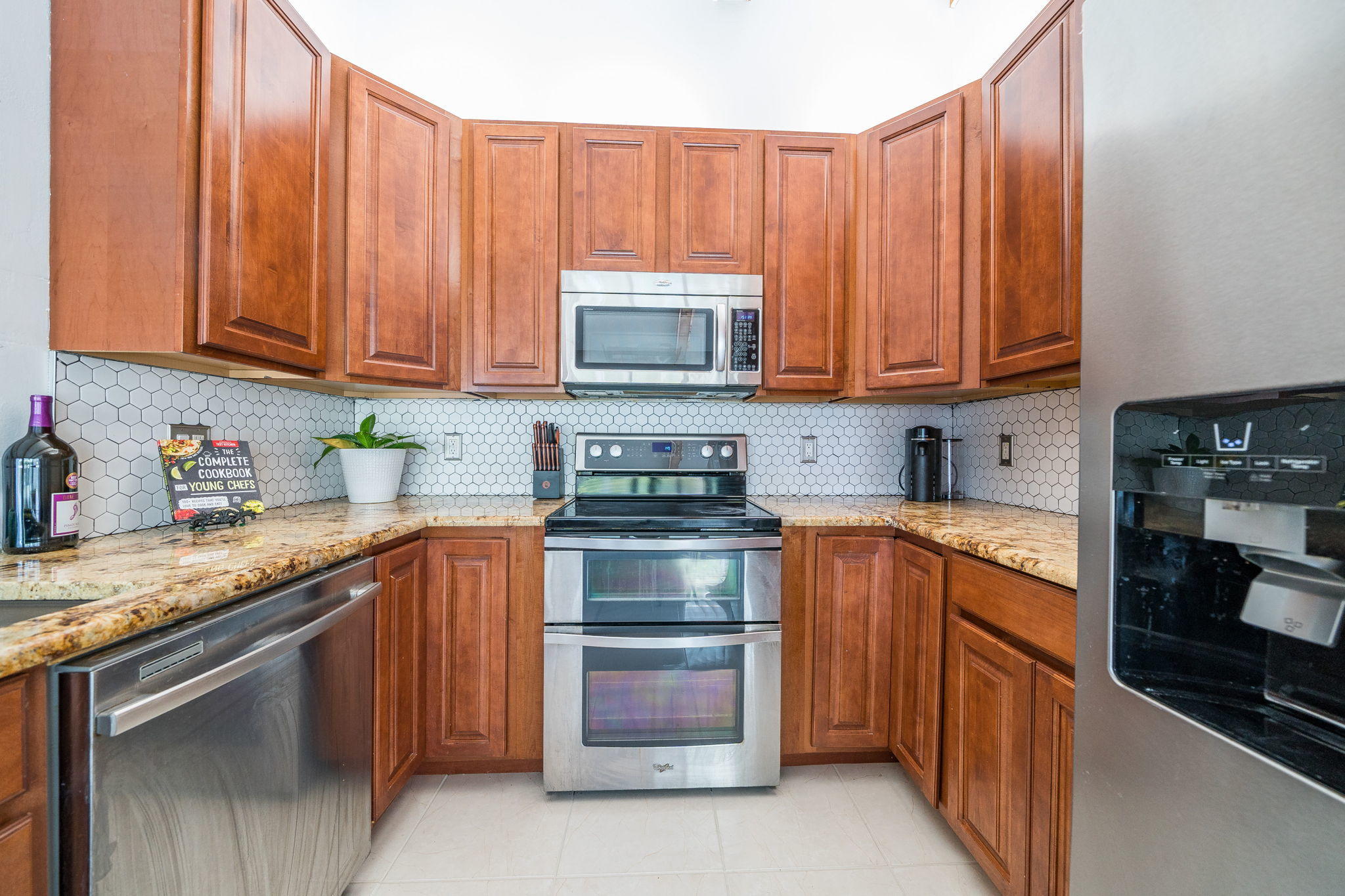 1877 Shower Tree Way Wellington, FL 33414 - Photo 20 of 47 a kitchen with granite countertop wooden cabinets and a stove top oven