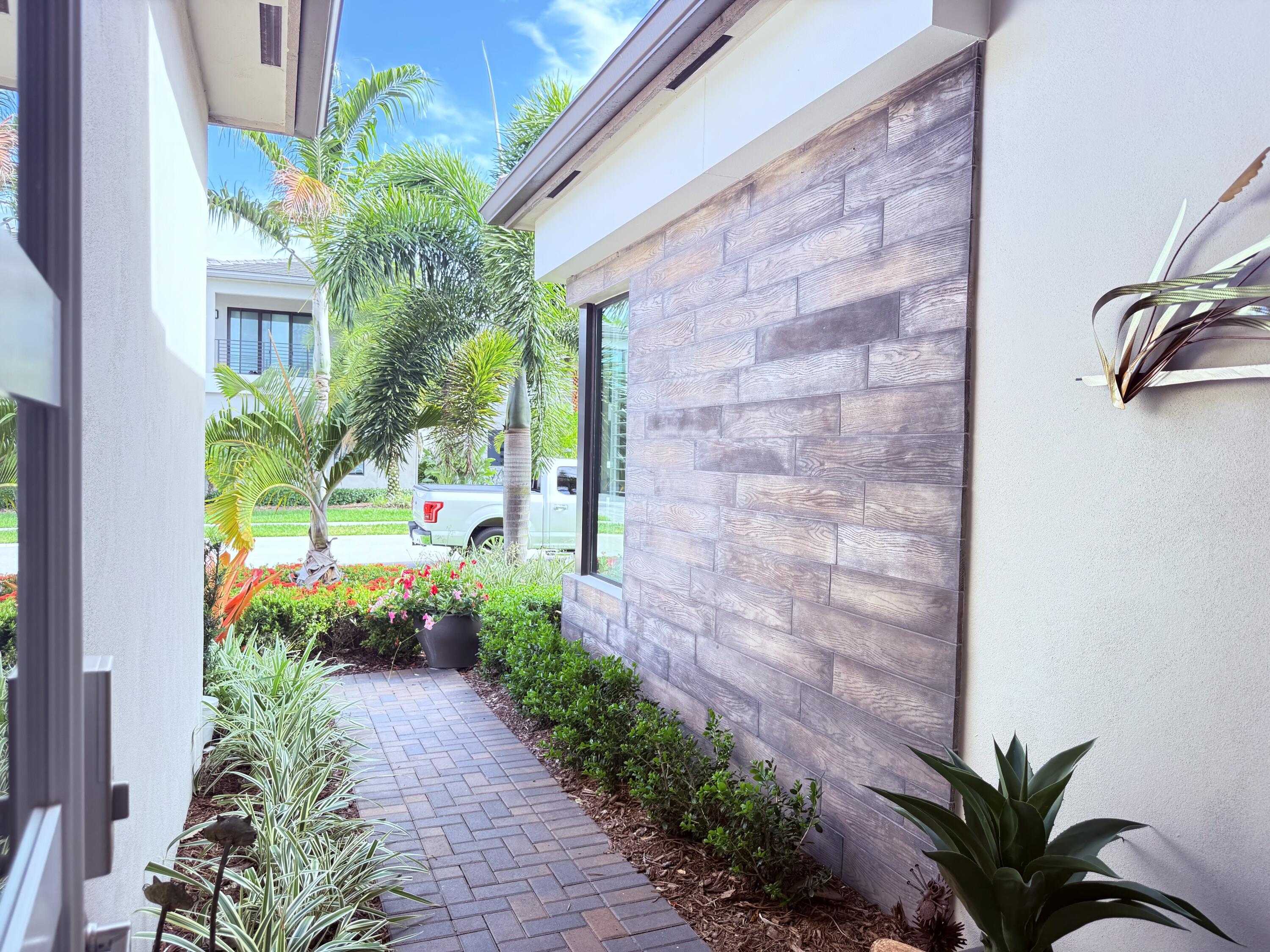 8575 Dearborn River Way Boca Raton, FL 33496 - Photo 2 of 32 a view of a pathway with plants and brick walls