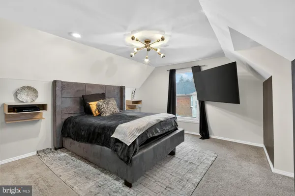 a bedroom with a bed a mirror on dresser and a chandelier