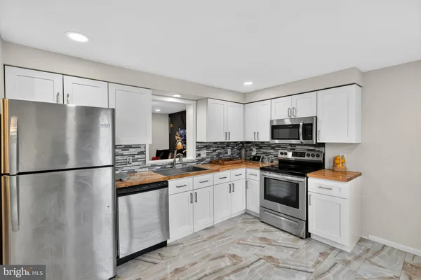 a kitchen with stainless steel appliances granite countertop a refrigerator sink stove microwave and cabinets