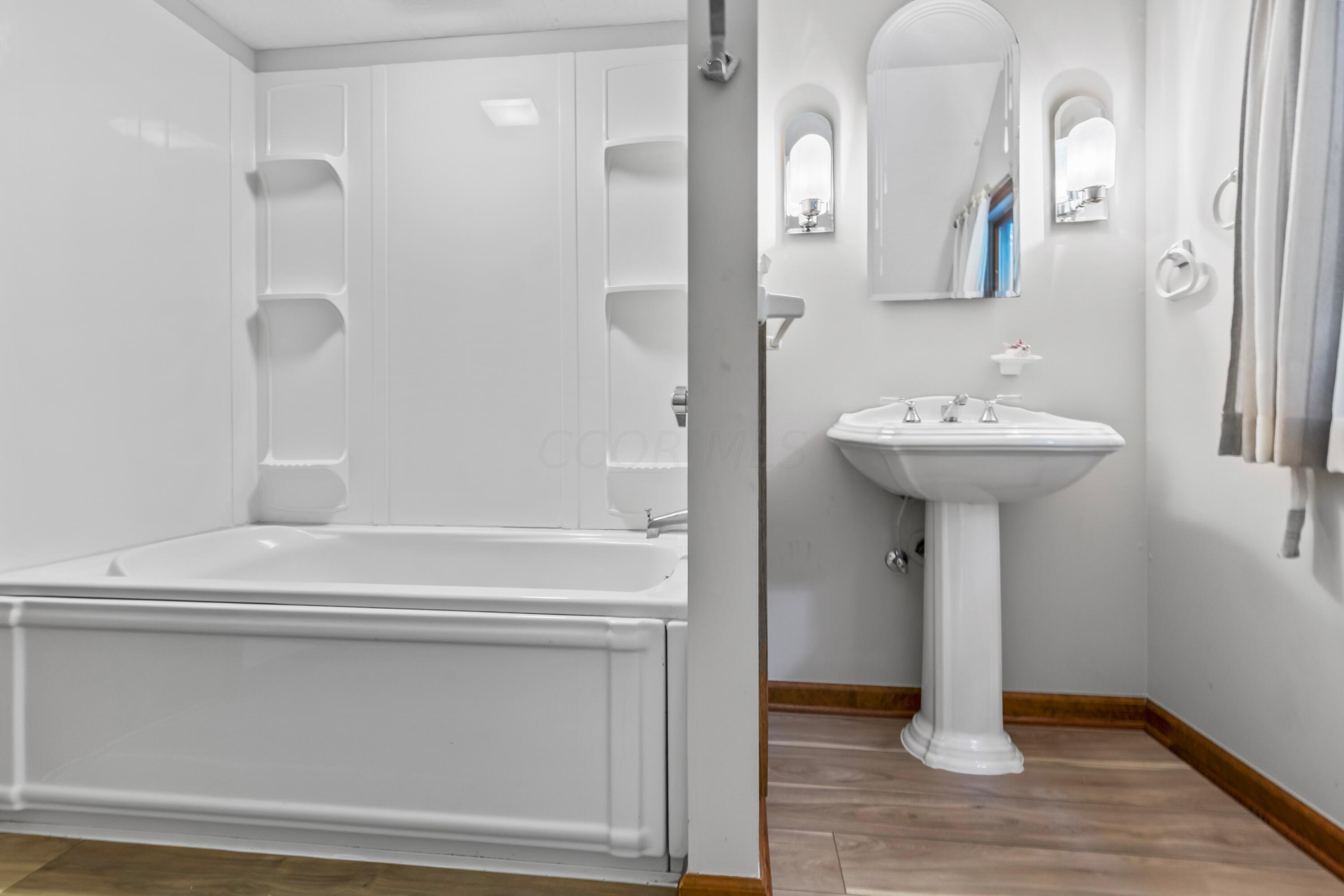 6940 Graham Road Mount Vernon, OH 43050 - Photo 38 of 70 • New luxury vinyl plank
flooring ~ 06/2024
• Ivory painted walls
• Angled ceiling
• Tub/shower combination
• Pedestal sink
• Wall mounted light
