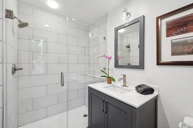 a bathroom with a granite countertop sink toilet and large mirror