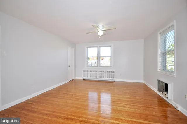 a view of an empty room with a window and wooden floor