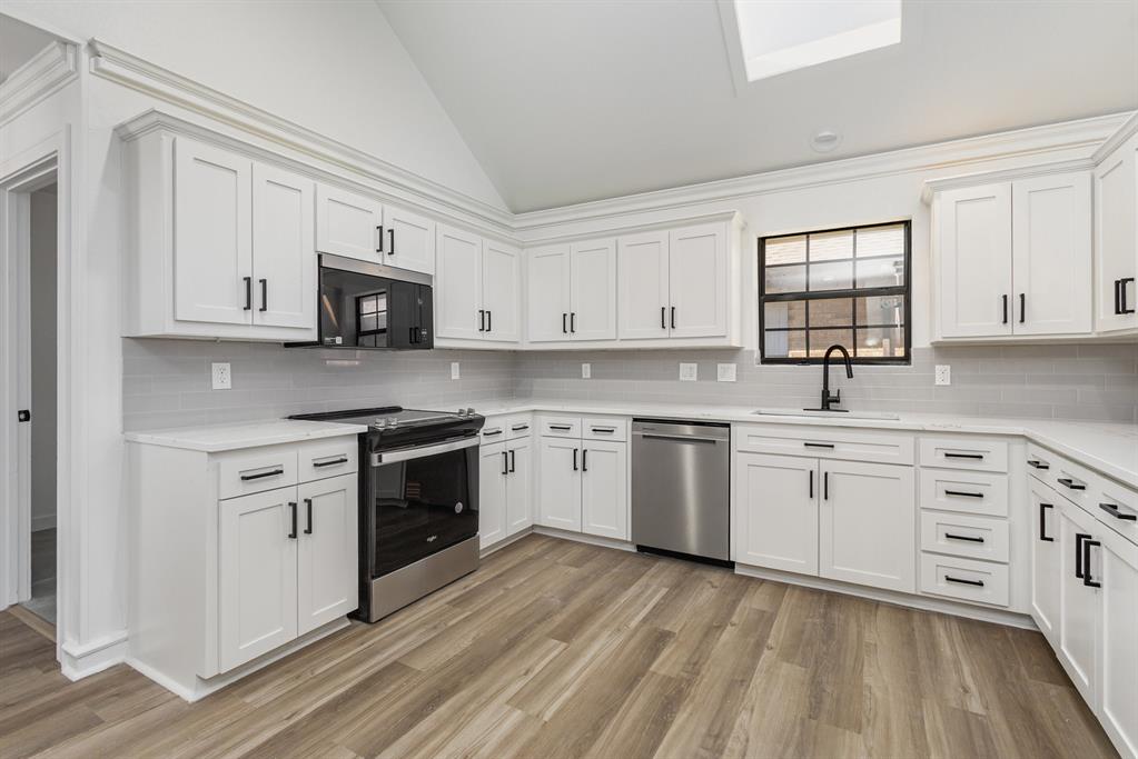 922 Sycamore Creek Road Allen, TX 75002 - Photo 16 of 38 Kitchen with lofted ceiling, stainless steel appliances, white cabinets, backsplash, and light stone countertops