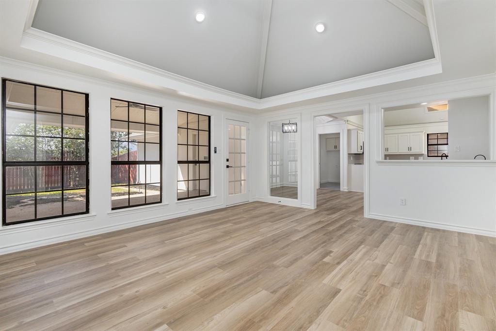922 Sycamore Creek Road Allen, TX 75002 - Photo 19 of 38 Unfurnished living room featuring light wood-style floors, crown molding, high vaulted ceiling, and a raised ceiling