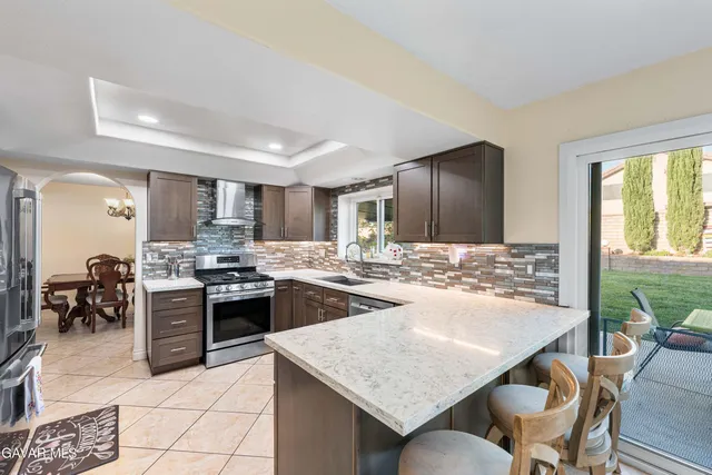 a kitchen with stainless steel appliances granite countertop a stove top oven a sink a dining table and chairs with wooden floor