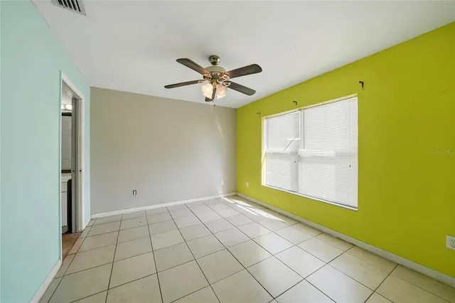 a view of an empty room with a window and a kitchen