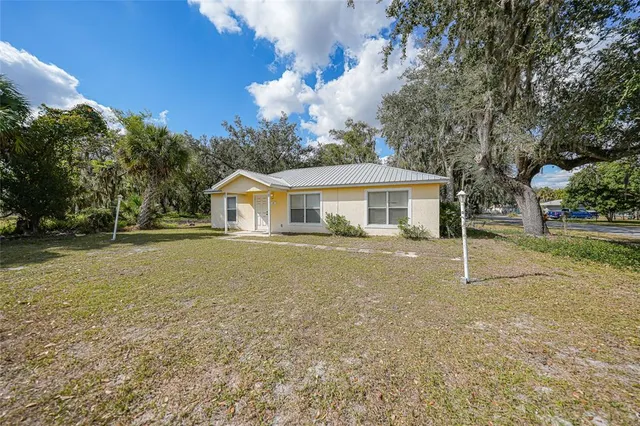 a view of a house with a yard and large tree
