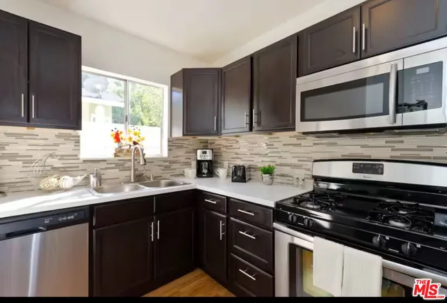 a kitchen with stainless steel appliances a sink stove and microwave