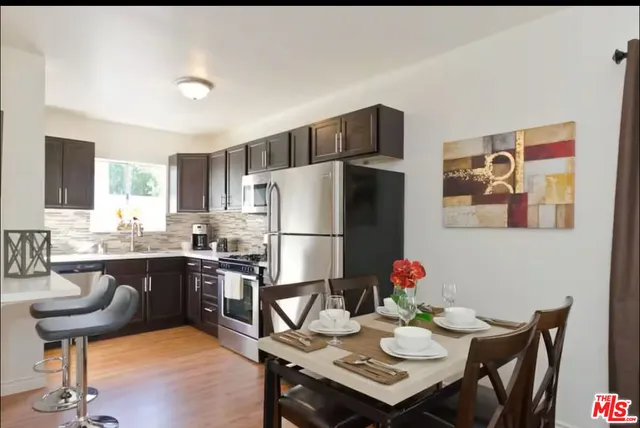 a kitchen with a dining table chairs refrigerator and microwave