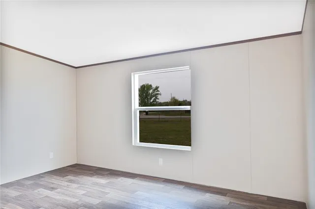 a view of an empty room with a window and wooden floor
