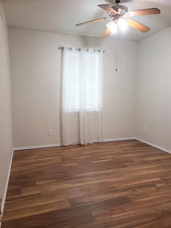 a view of an empty room with window and wooden floor