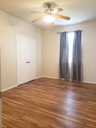a view of an empty room with window and wooden floor