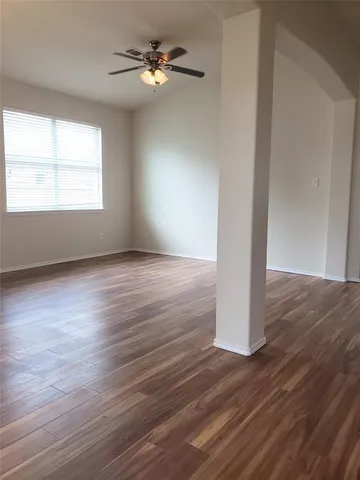an empty room with wooden floor chandelier fan and windows