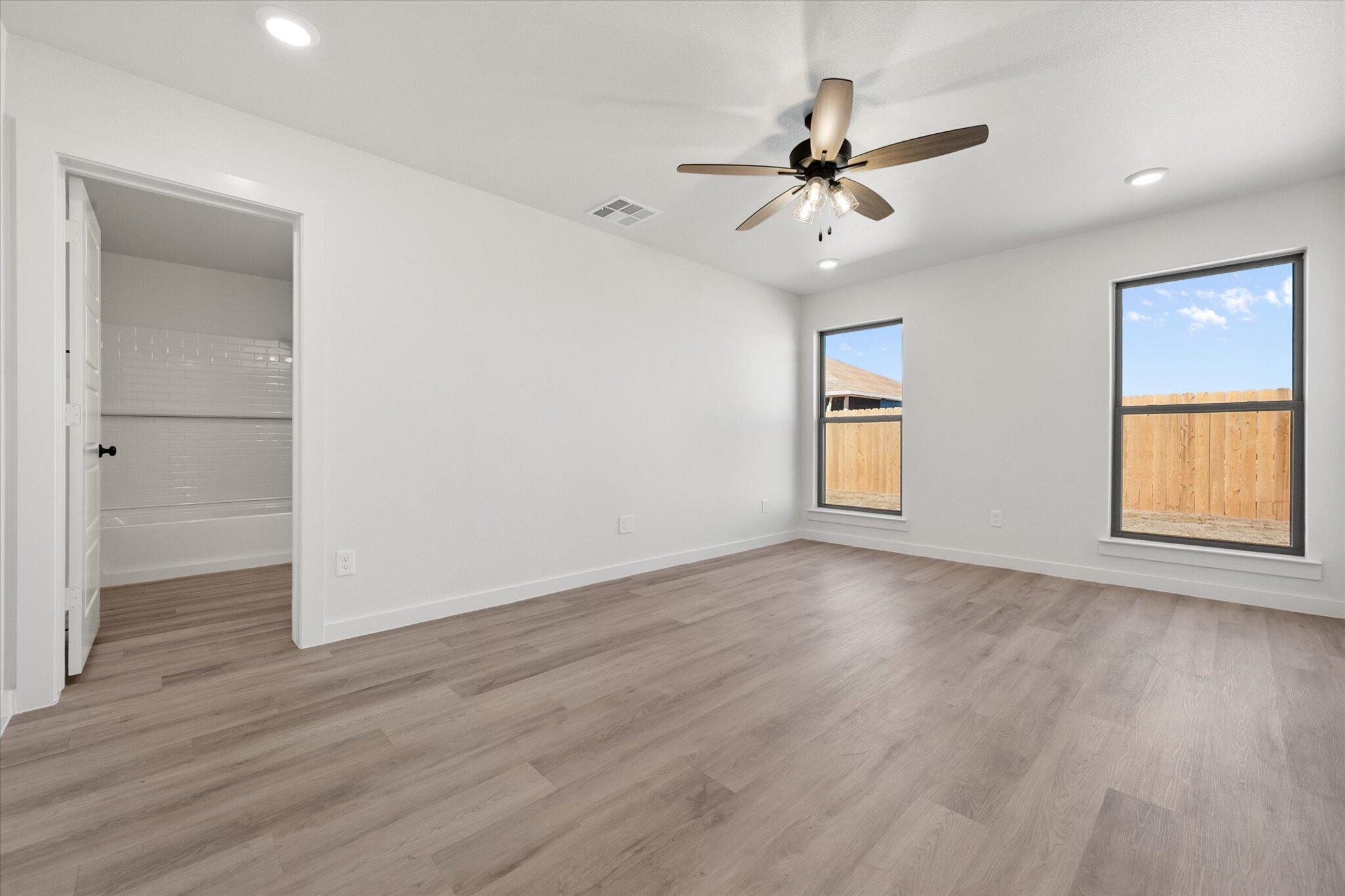 2403 Helena Avenue Lubbock, TX 79407 - Photo 17 of 25 an empty room with wooden floor chandelier fan and windows