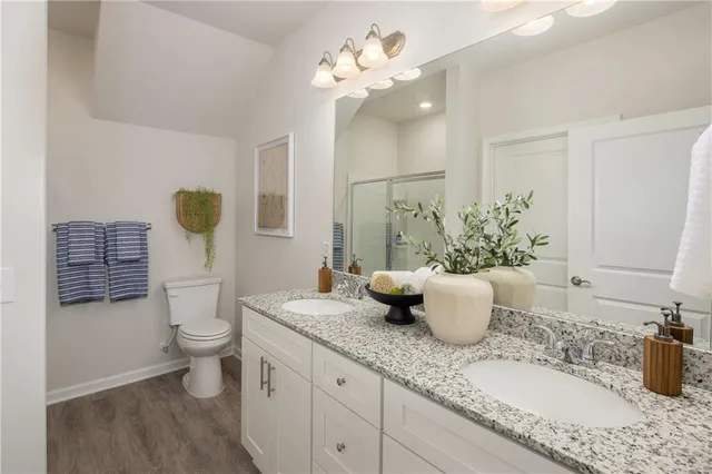 a bathroom with a granite countertop sink a toilet and shower