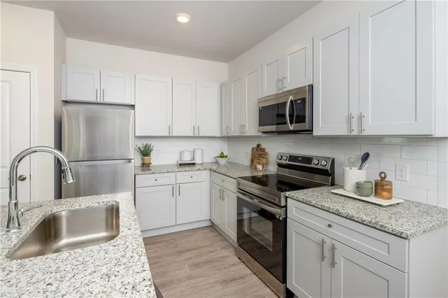 a kitchen with granite countertop white cabinets and stainless steel appliances