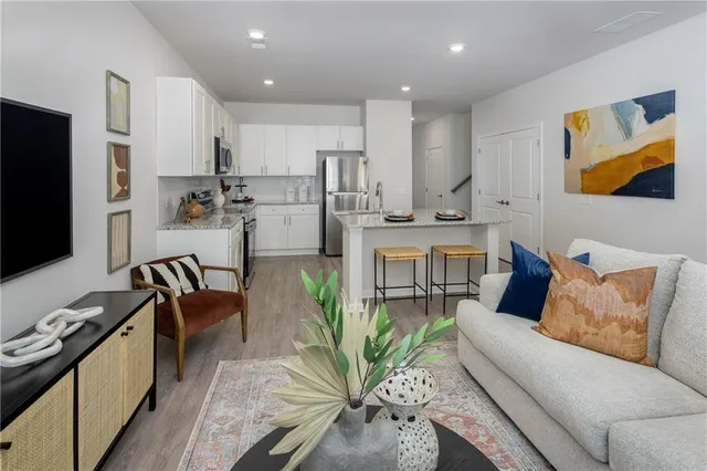 a living room with stainless steel appliances furniture and a kitchen view