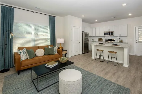 a living room with furniture a wooden floor and a refrigerator