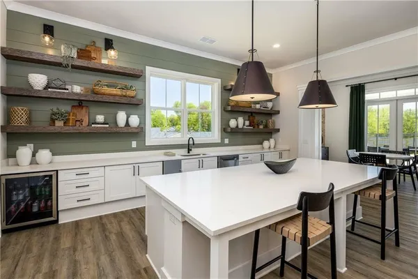 a kitchen with stainless steel appliances granite countertop a stove a refrigerator a sink a dining table and chairs with wooden floor
