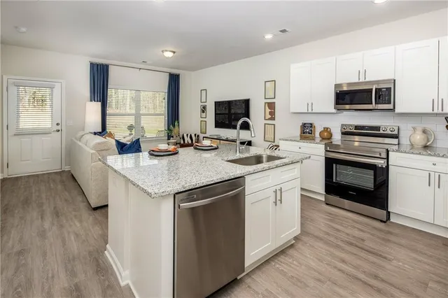 a kitchen with stainless steel appliances granite countertop a sink stove microwave and refrigerator